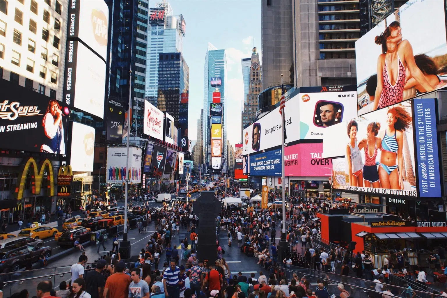 Digital billboard advertising in Times Square, New York, showing large LED screens and crowds
