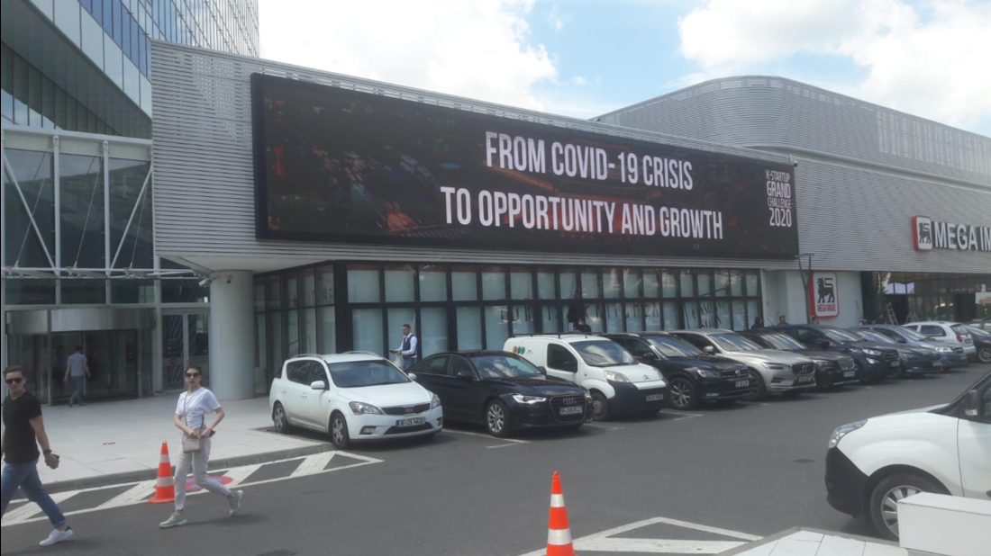 K-Startup Grand Challenge 2020 'From COVID-19 crisis to opportunity and growth' creative on a large screen across a corporate building facade in Bucharest