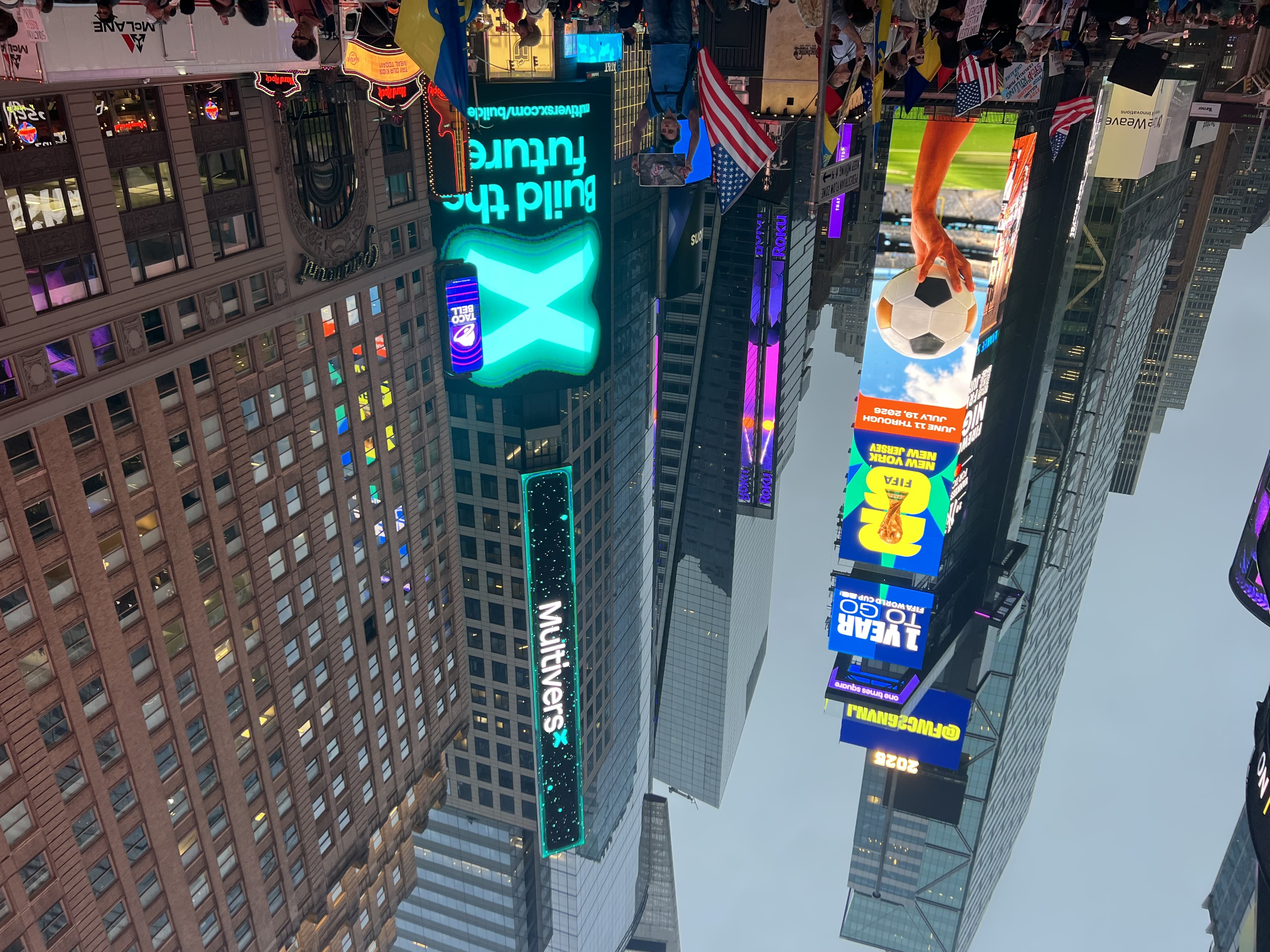 Vertical multi-story MultiversX blockchain brand takeover LED billboard on a Times Square high-rise facade with teal neon border, surrounded by Midtown Manhattan towers