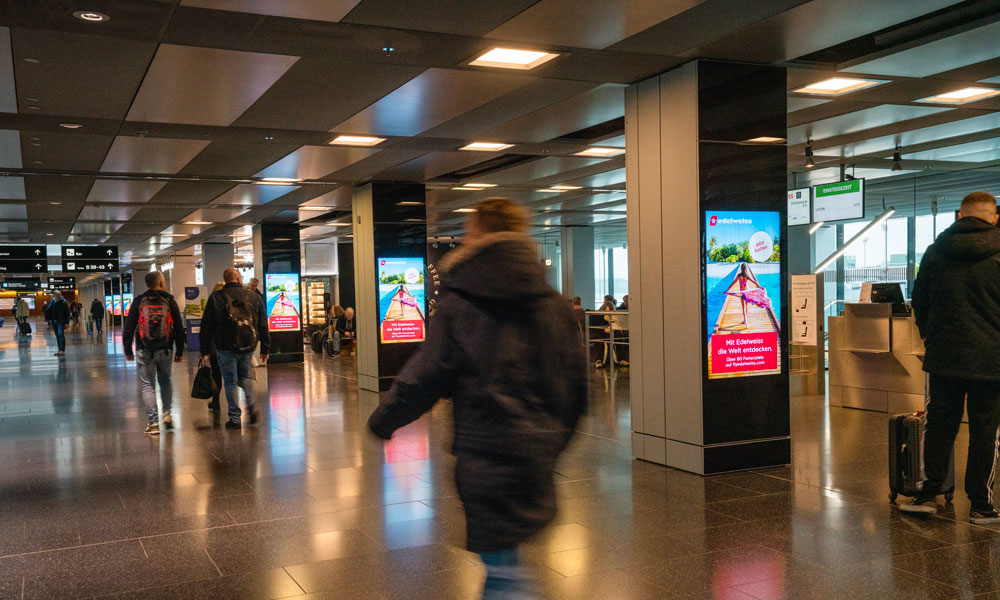 Zurich Airport, Departures hall · digital pillar network, real DOOH inventory bookable by the hour on Blindspot