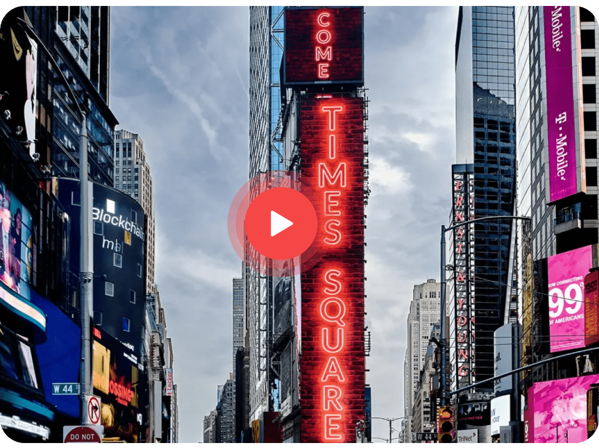Vertical neon sign reading 'Come to Times Square' on a tall building amidst city skyscrapers.