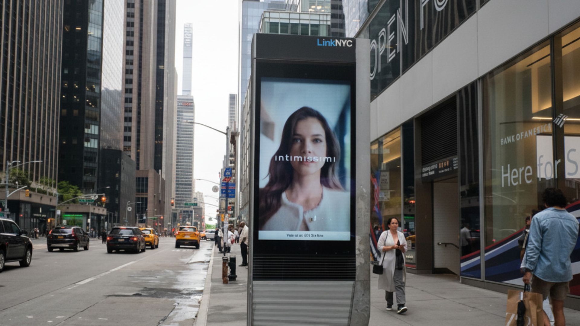 LinkNYC digital kiosk displaying an Intimissimi lingerie campaign with a store visit CTA on a Midtown Manhattan sidewalk near Bank of America, yellow cabs, and pedestrians on a busy New York City avenue.